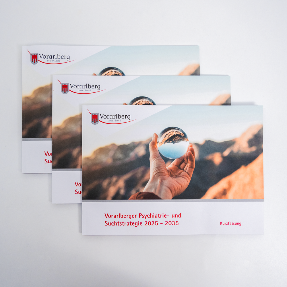 Landesregierung Vorarlberg Suchtstrategie 3 Broschüren geschlossen mit einer Hand, die eine Glaskugel hält